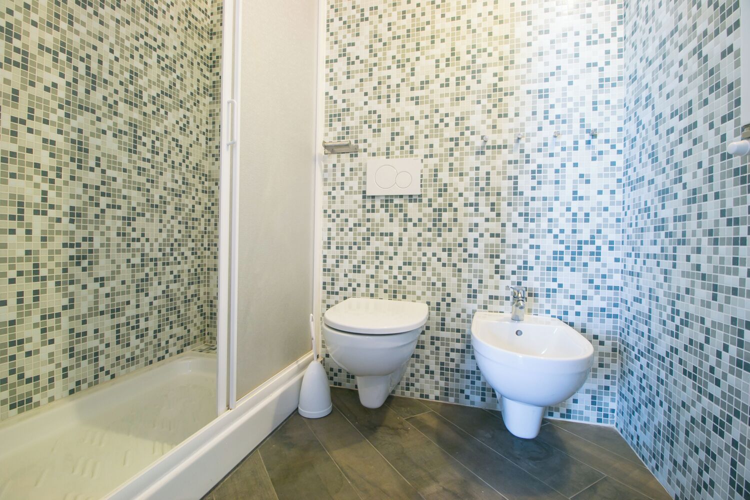 Un bagno con pareti in mosaico, un water e un bidet.