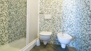 Un bagno con pareti in mosaico, un water e un bidet.