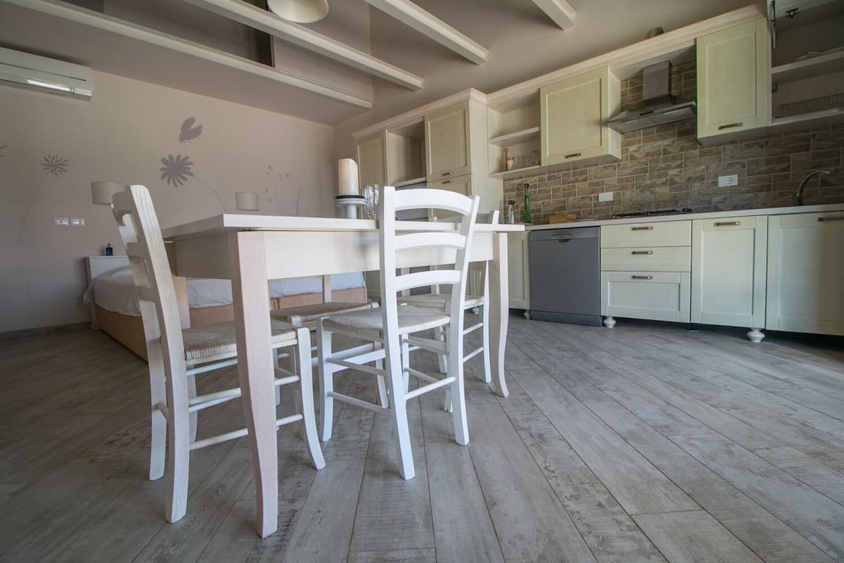 Una cocina con armarios blancos, una mesa de comedor con sillas y un lavavajillas.