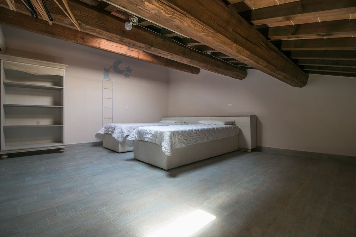 Un dormitorio con dos camas, un armario y una escalera apoyada en la pared.