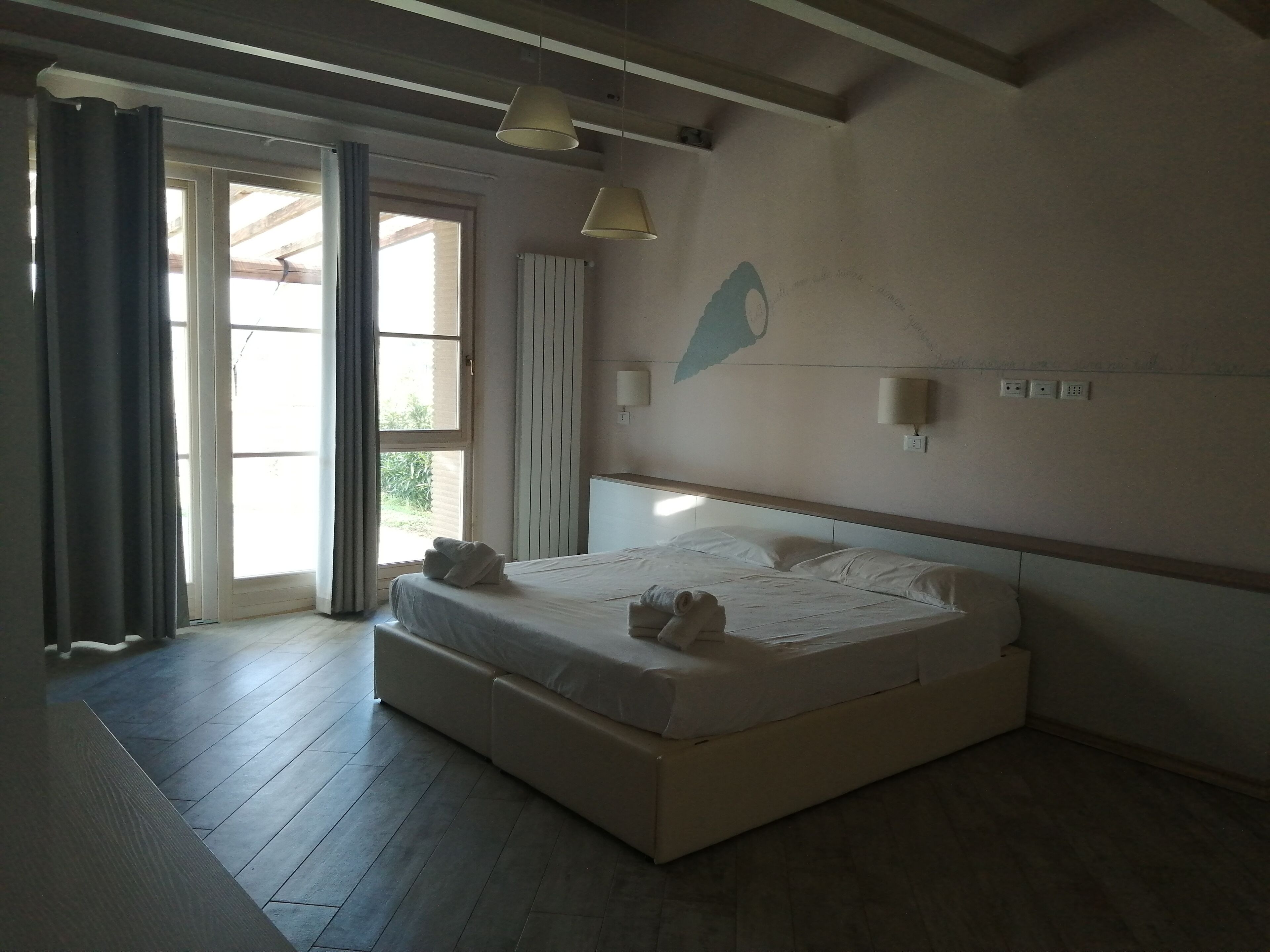 Un dormitorio con una cama grande, ventilador de techo y ventana con cortinas.