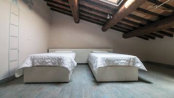 Un dormitorio pequeño estilo altillo con dos camas individuales, un tragaluz y vigas de madera a la vista.