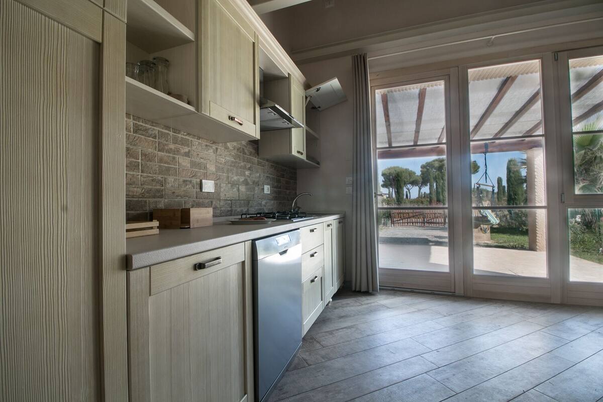 Una cocina moderna con salpicadero de piedra, armarios de madera y lavavajillas empotrado.