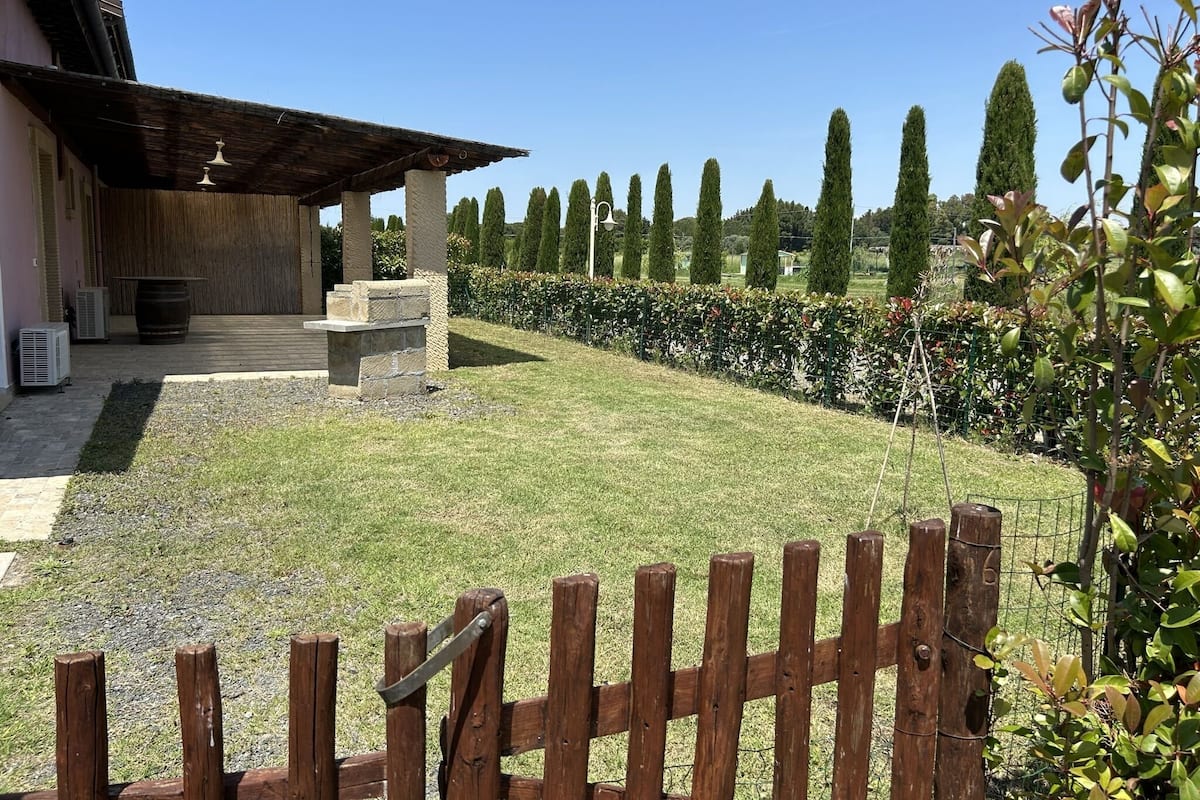 Un patio con una pérgola, escalones de piedra y una valla de madera.