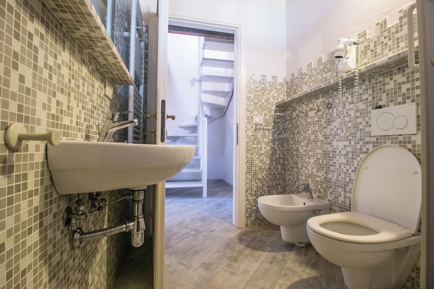 Ein Badezimmer mit Waschbecken, zwei Toiletten und einer Dusche.