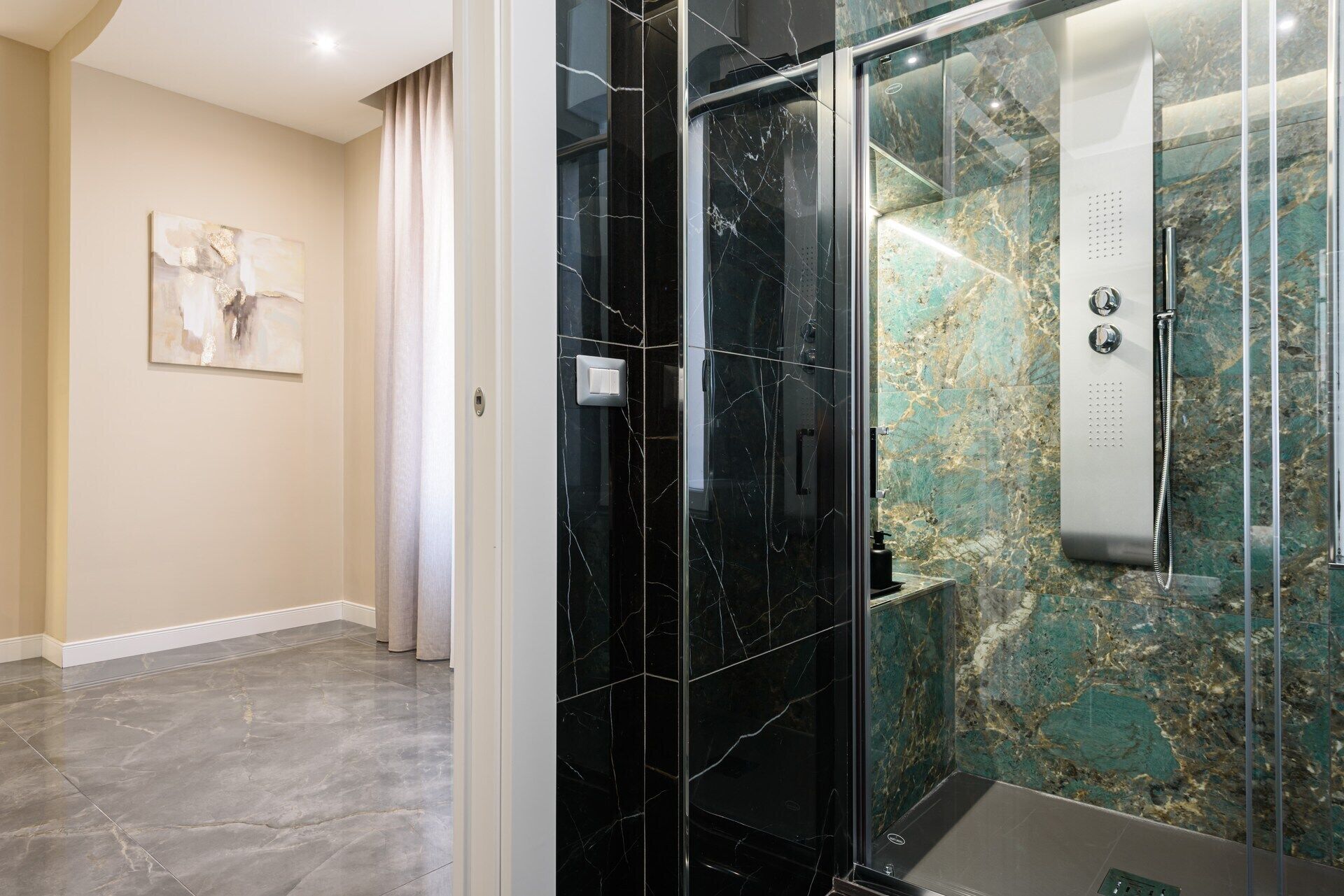 A modern bathroom with a glass-enclosed shower, marble walls, and a minimalist design.