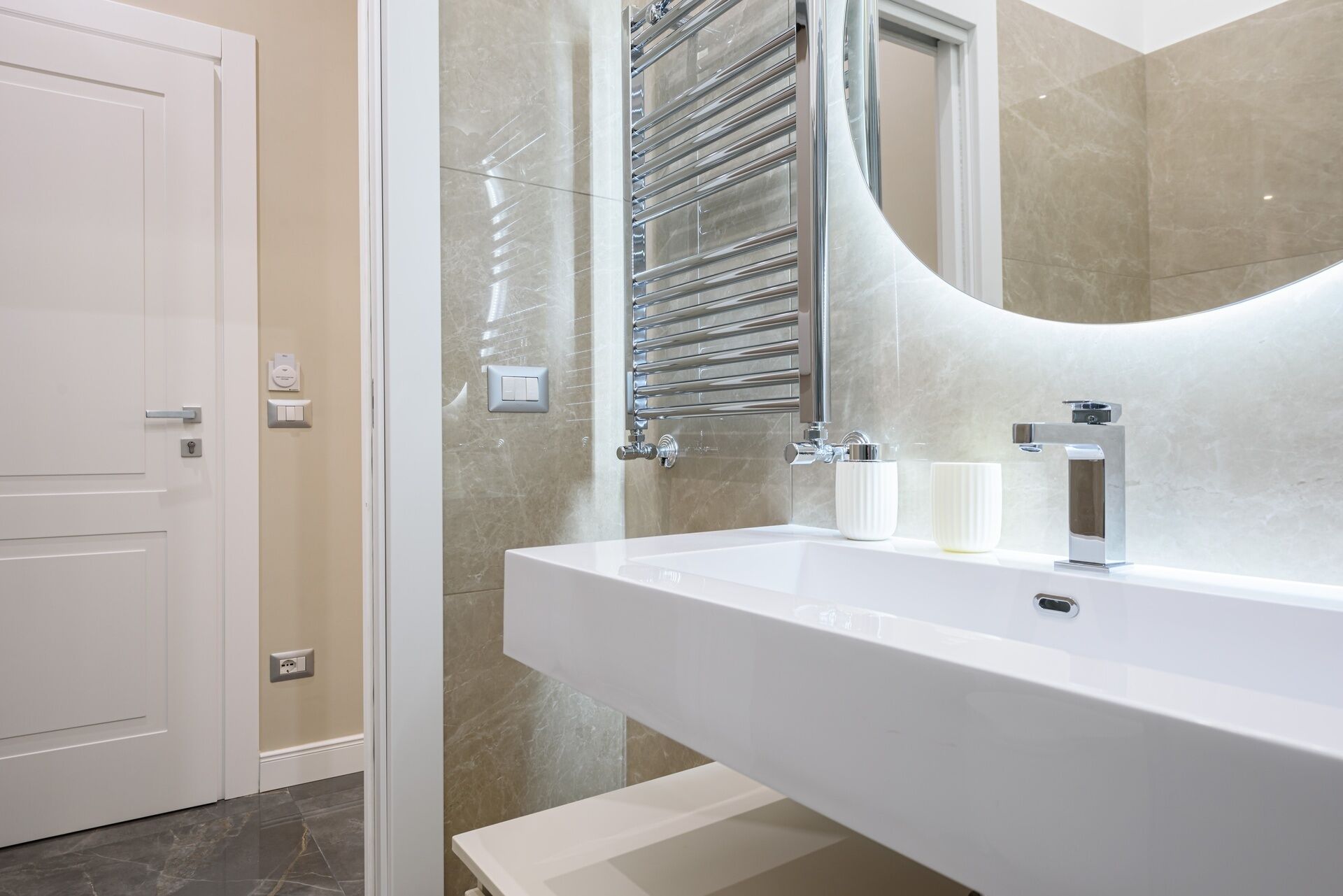 A modern bathroom with a white sink, chrome fixtures, and a large mirror.