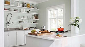 Una cucina moderna con mobili bianchi, un'isola centrale con sgabelli e una finestra che lascia entrare luce naturale.