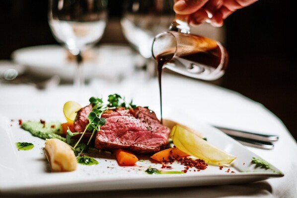 A steak dish with vegetables and sauce on a plate.