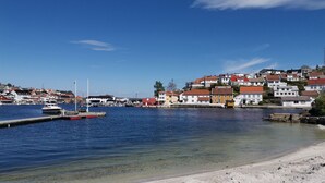 Un pueblo costero con un puerto deportivo, playa de arena y edificios coloridos.