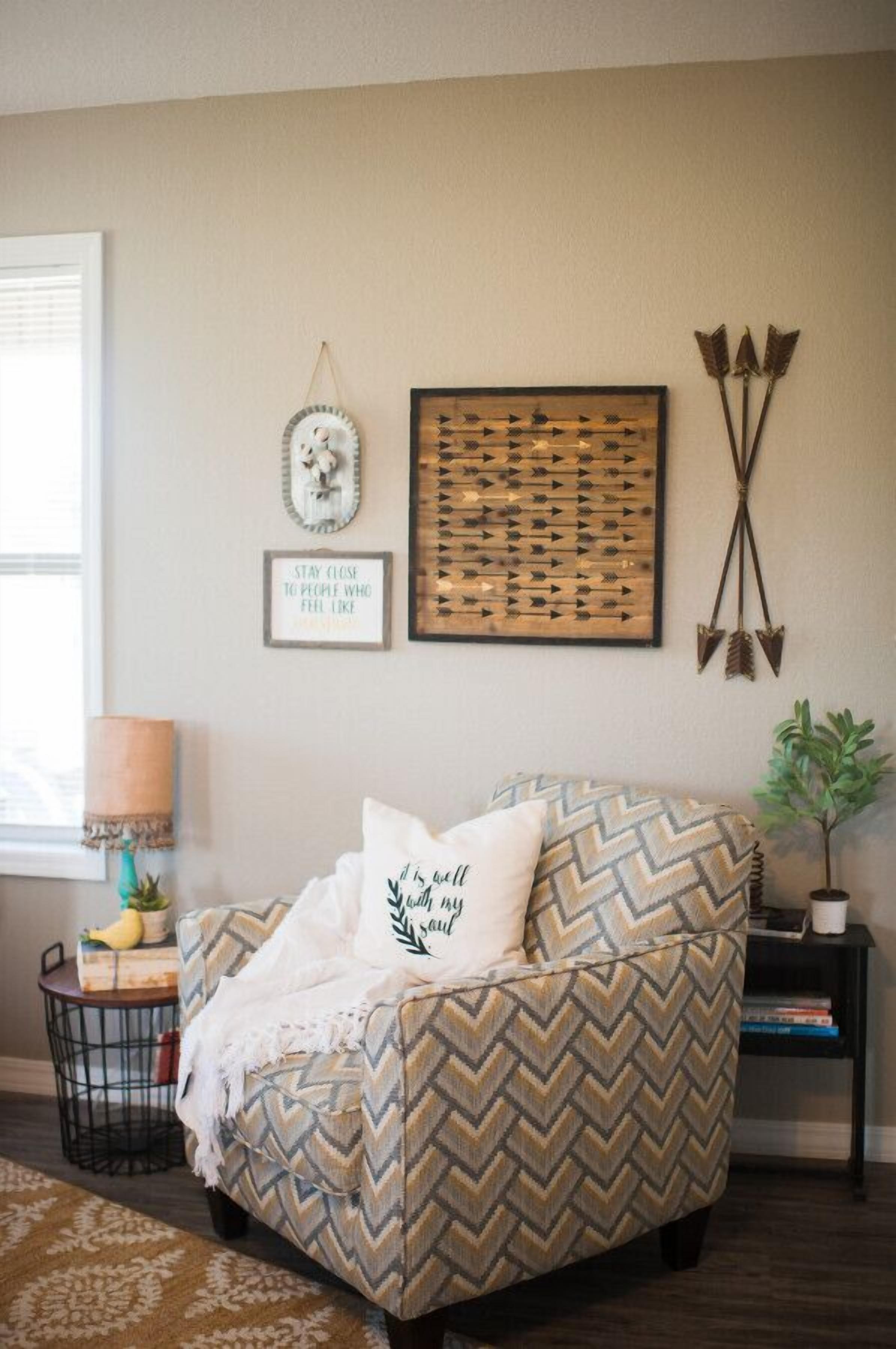 Un salón acogedor con un sillón de patrón escalonado, un reloj de pared, una frase motivacional y una obra de arte con una flecha enmarcada.