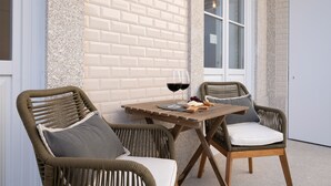 Un espacio de descanso con sillas de mimbre y una mesa de madera, que incluye una copa de vino tinto y una bandeja de frutas.