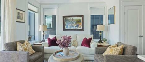A living room with two sofas, a coffee table, and a painting on the wall.