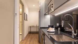 A modern kitchen with stainless steel appliances, a black countertop, and a wooden floor. - Charming Studio for Two in Beautiful Chamberí (Madrid)