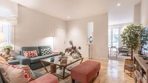 A modern living room with a grey sofa, red patterned ottoman, and a glass coffee table. - Elegant 2-Bed Apartment in Salamanca, Madrid (Madrid)