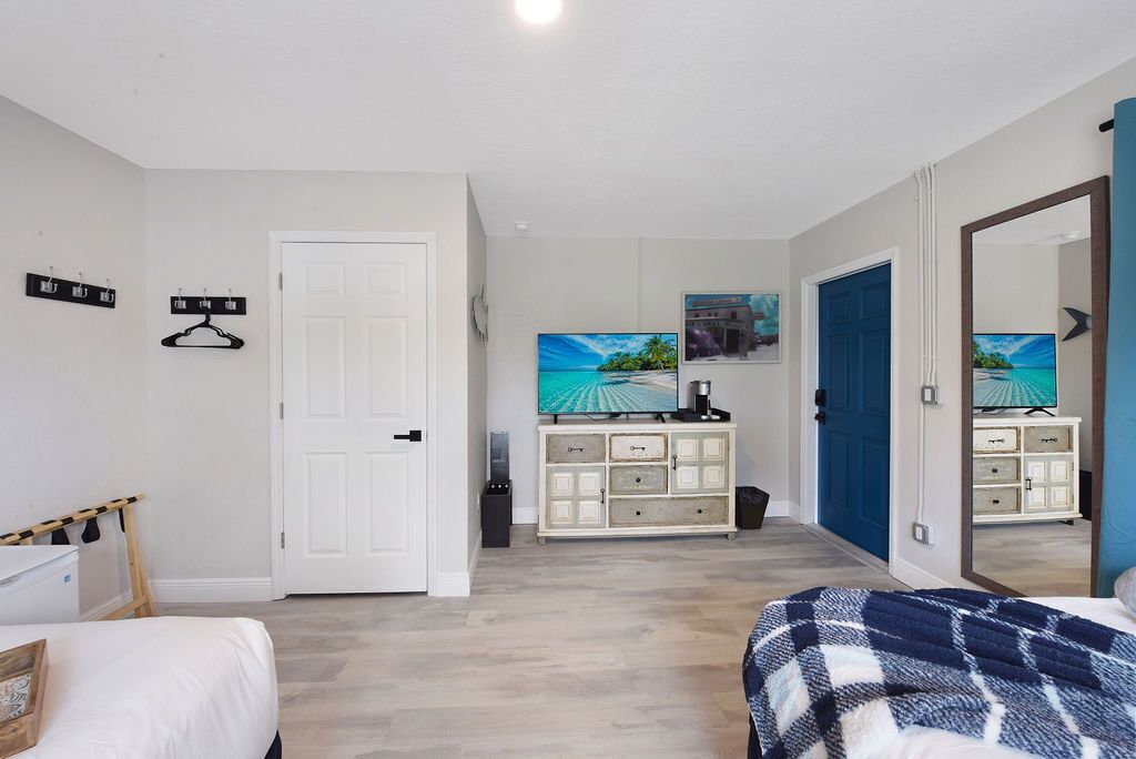 A bedroom with a bed, a dresser, a TV, and a wardrobe.
