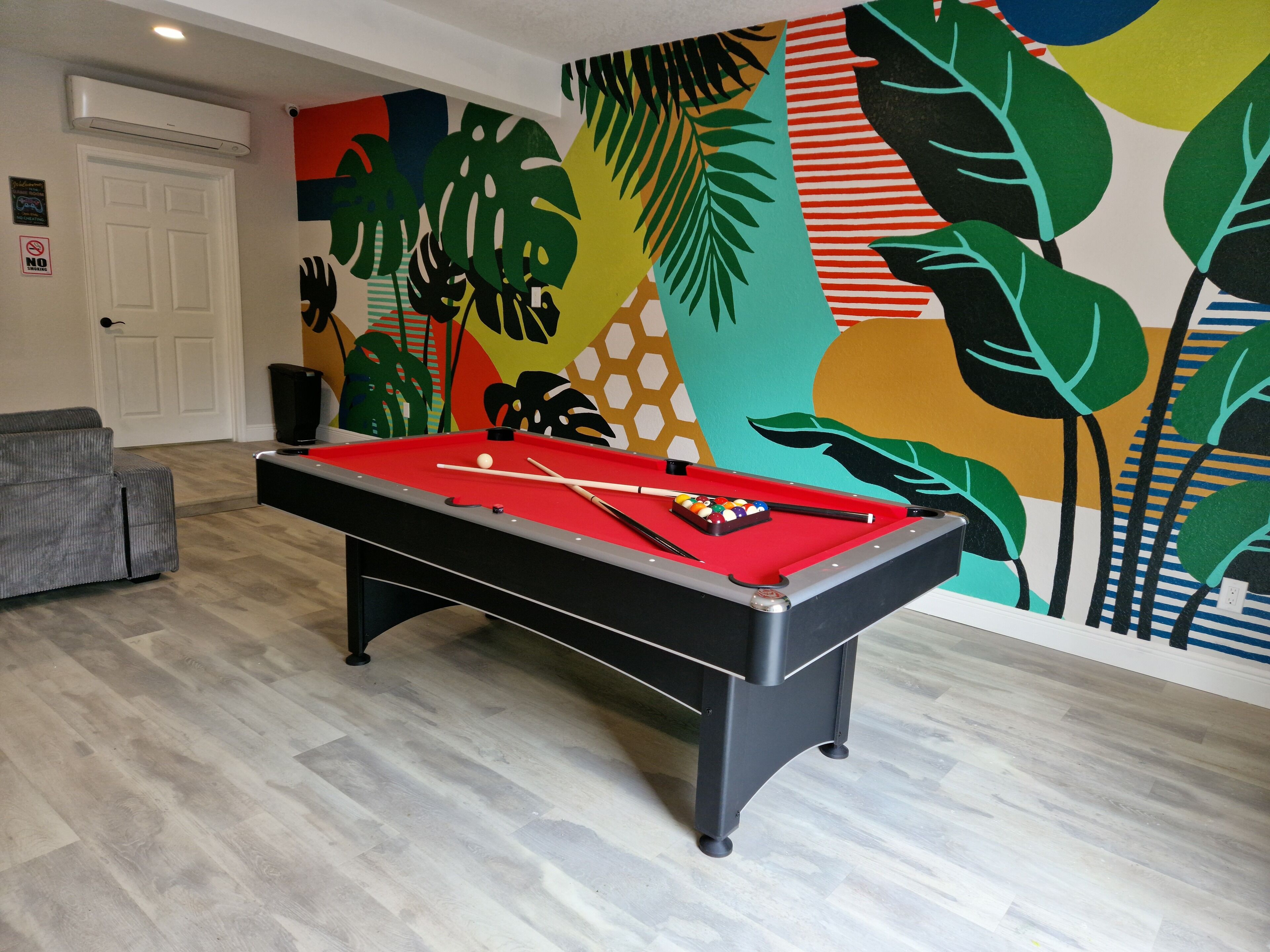 Uma mesa de bilhar em um ambiente com um mural colorido na parede.