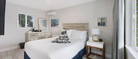 A neatly arranged bedroom with a large bed, bedside tables, a dresser, and artwork on the walls.
