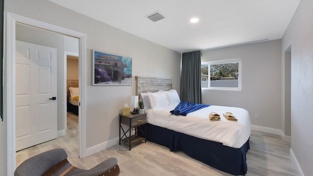 Une chambre d’hôtel avec un lit, une table de chevet, une chaise et une fenêtre.