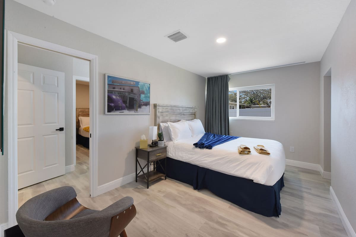 Une chambre d’hôtel avec un lit, une table de chevet, une chaise et une fenêtre.