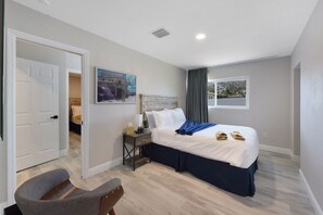 Una habitación de hotel con cama, mesita de noche, silla y ventana.