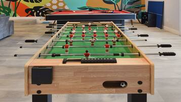 Una taula de futbolí en una habitació amb un mural de colors a la paret.