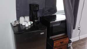 A compact kitchenette with a refrigerator, microwave, coffee maker, and a small wooden drawer unit. - 068A Cozy Studio Grand Canyon South Rim Sleeps-2 (Williams)
