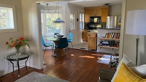 Amplia sala de estar con comedor, cocina y un rincón de descanso acogedor con sofá y lámpara.