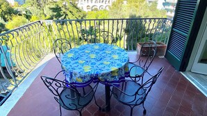 A balcony with a table and chairs, a tiled floor, and a view of buildings and trees. - Casa Mar - Apartment with Pool and Panoramic Terrace in the Heart of Sorrento (Sorrento)