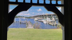 A view through a window with a decorative frame, overlooking a marina with boats and a bridge in the background. - Dock, Dine, & Unwind: The Ultimate Waterfront Glamp Spot (Edgewater)