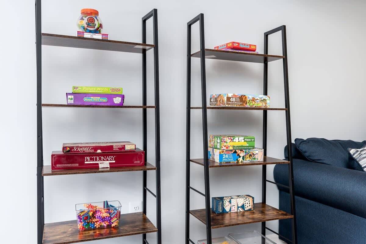 Two black metal shelves with various board games and a container of colorful beads.