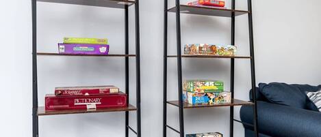 Two black metal shelves with various board games and a container of colorful beads.