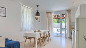 A dining area with a table, chairs, and a hanging light fixture.
