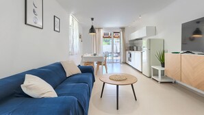 A modern living room with a blue sofa, a round coffee table, and a dining area with a white table and chairs.