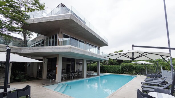 A modern building with a pool area, outdoor seating, and a covered patio.