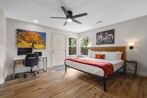 Un dormitorio con cama, escritorio, silla y obras de arte.