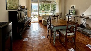 Een eethoek met een houten tafel en stoelen, een piano en een televisie op een dressoir.