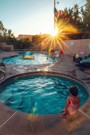 A swimming pool with a child sitting by the edge, surrounded by lounge chairs and a sunlit sky. - Sugar Loaf Lodge (Sedona)