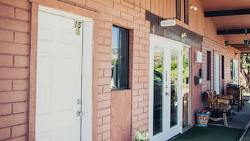 A row of single-story buildings with a brick facade, numbered doors, and a covered porch area.