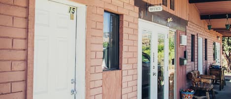 A row of single-story buildings with a brick facade, numbered doors, and a covered porch area.