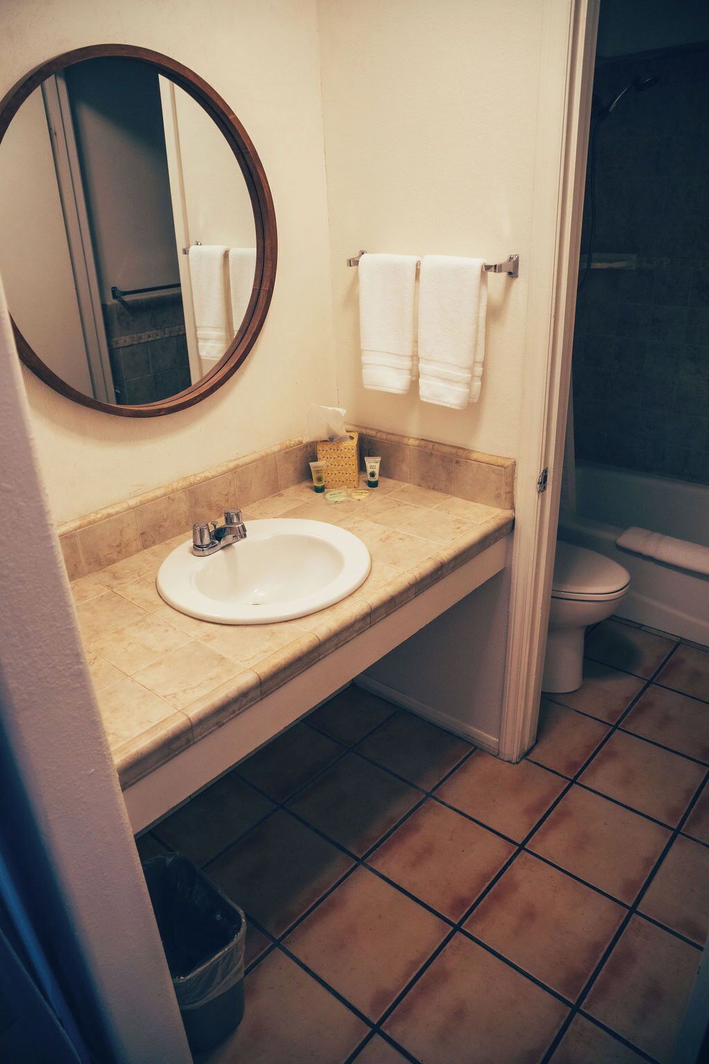 A bathroom with a round mirror, a sink, and a toilet.