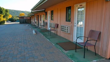 Un motel con estacionamiento de adoquines y una hilera de habitaciones con entradas individuales.