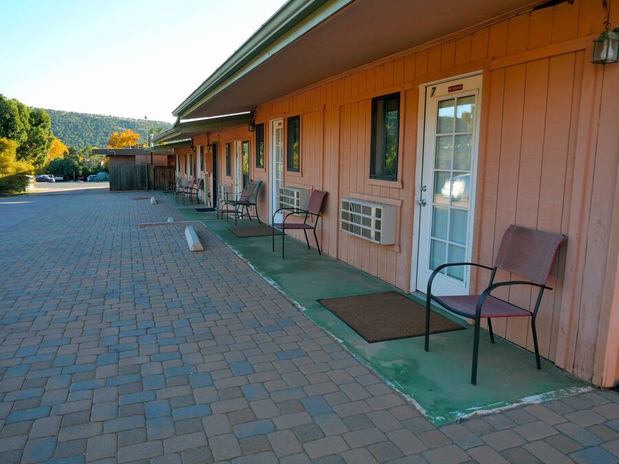 Un motel con estacionamiento de adoquines y una hilera de habitaciones con entradas individuales.