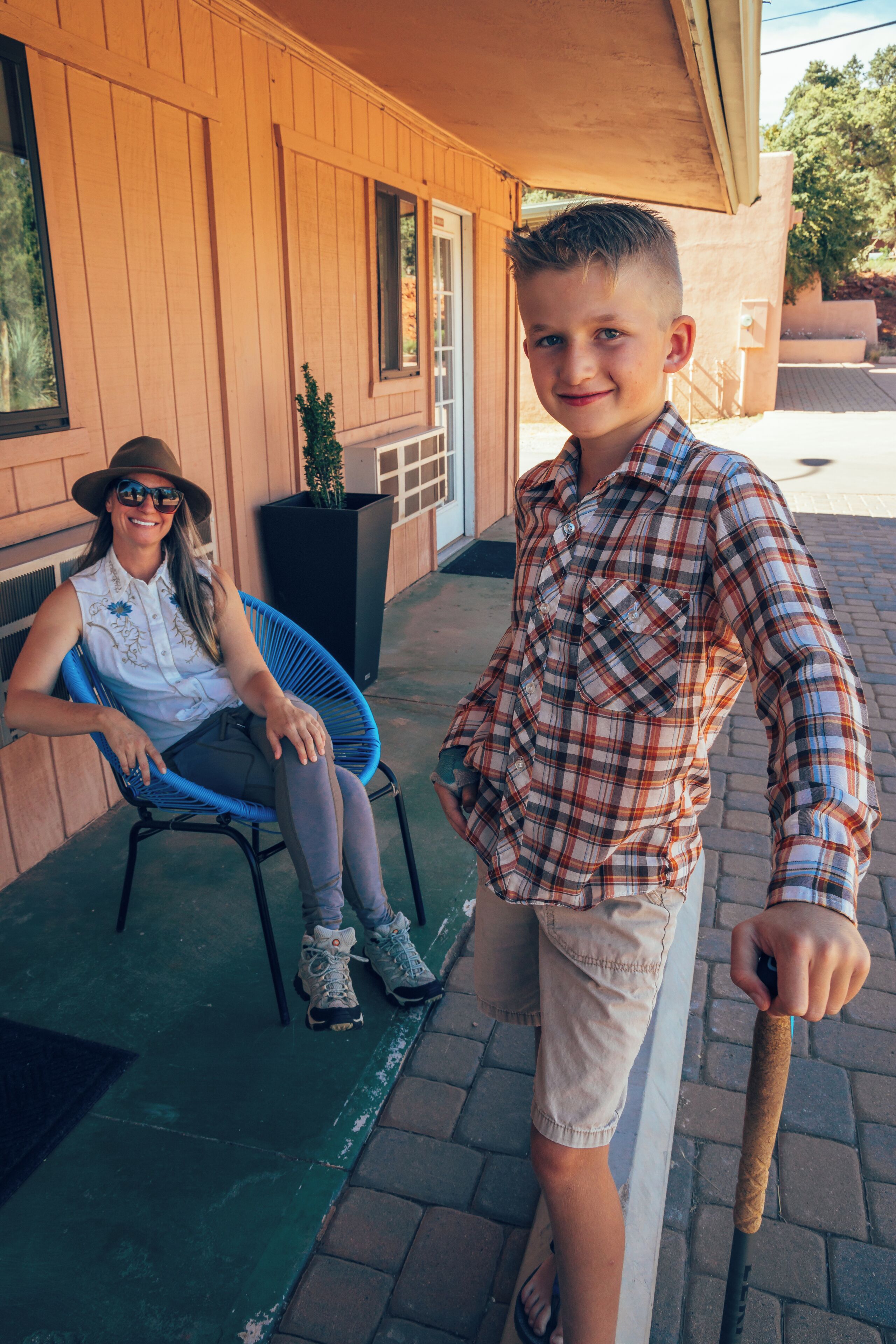 A person sitting on a blue chair outside a building with wooden siding.