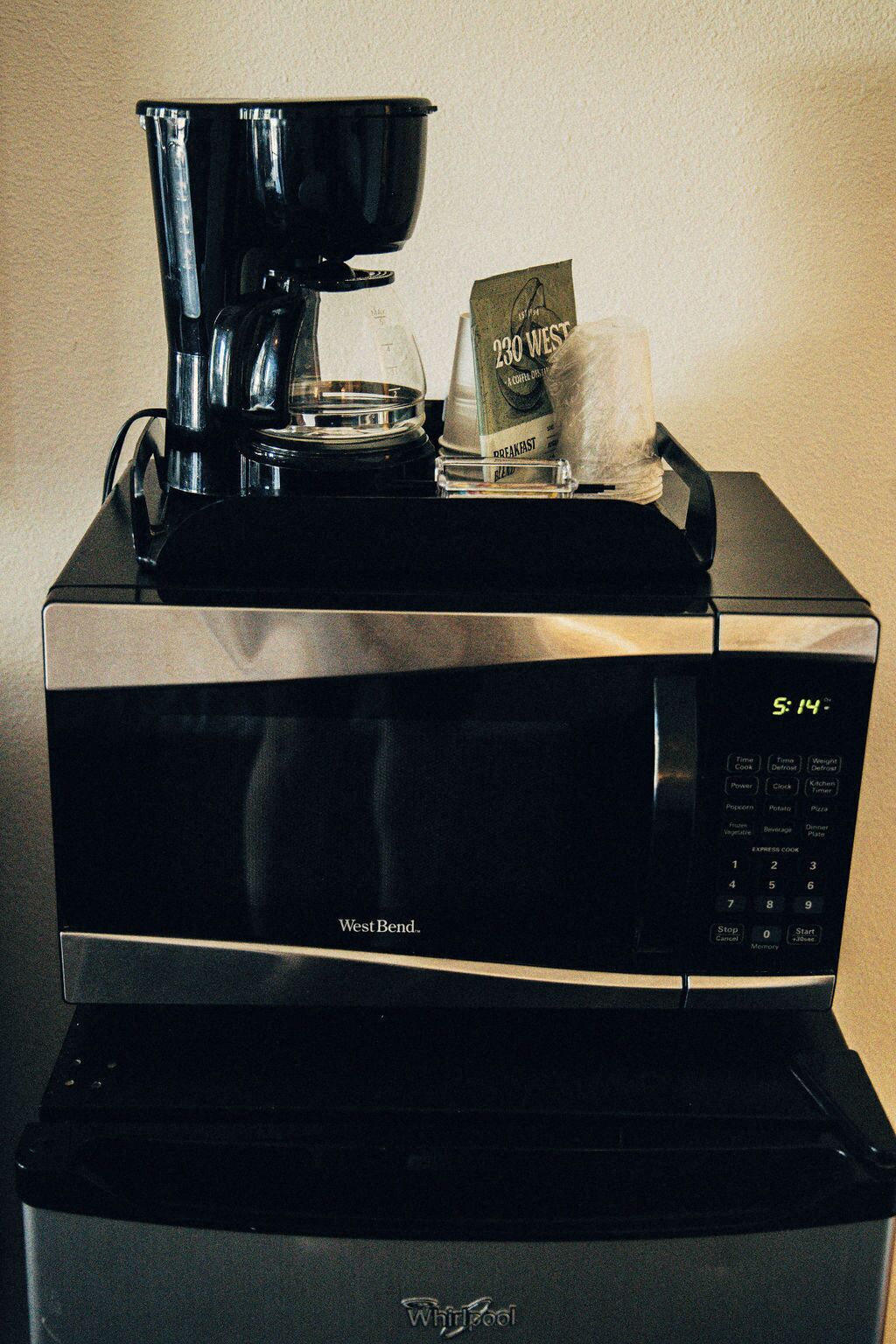 Un four à micro-ondes West Bend, avec une cafetière et un paquet de café West Bend posés dessus.
