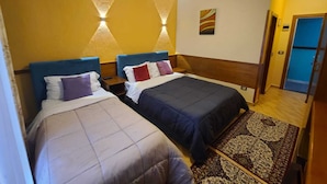 Habitación de hotel con dos camas, una alfombra estampada y un cuadro en la pared.