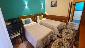Habitación de hotel con dos camas individuales, un escritorio y una silla.