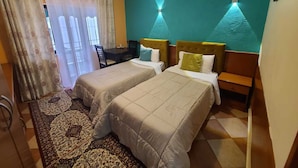 Una habitación de hotel con dos camas, un escritorio y una alfombra estampada.