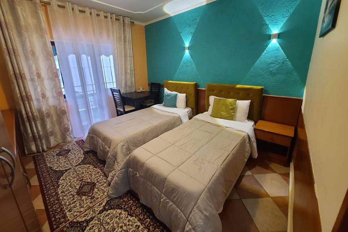 A hotel room with two beds, a desk, and a patterned rug.