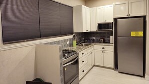 Una cocina moderna con armarios blancos, un refrigerador de acero inoxidable, un horno empotrado y una estufa a gas.